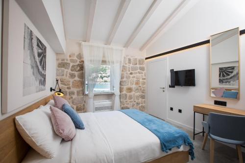 Un dormitorio con una cama, un escritorio y un televisor. en Bova Luxury Rooms, en Dubrovnik