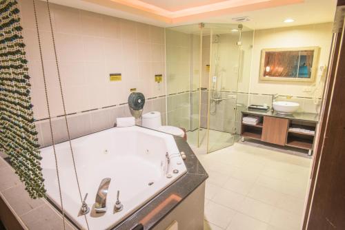 a bathroom with a tub and a glass shower at 亞歷山大汽車旅館 in Kaohsiung