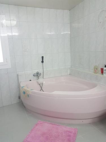 een witte badkamer met een bad en een roze kleed bij Son Roqueta in Palma de Mallorca