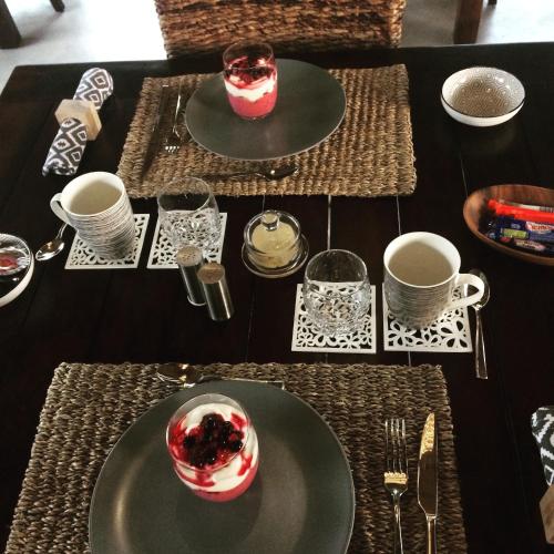 Una mesa con platos y tazas y un postre encima. en Bushbaby River Lodge, en Hoedspruit