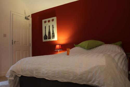 a bedroom with a white bed with a red wall at The Lodge B&B @ Cannock Chase in Cannock