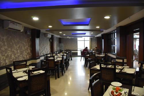 una sala da pranzo con tavoli, sedie e soffitto blu di Hotel Pybss a Itānagar