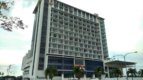 a tall white building with palm trees in front of it at UCSI Hotel Kuching in Kuching