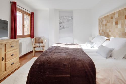 a bedroom with a large bed and a chair at Esquirós by FeelFree Rentals in Naut Aran