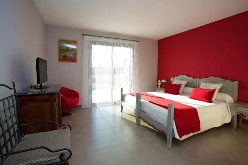 sypialnia z łóżkiem z czerwonymi ścianami i telewizorem w obiekcie Aubade en Luberon w mieście Cavaillon