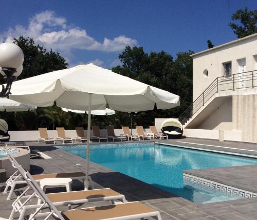 een zwembad met stoelen en een parasol naast een gebouw bij Residence de tourisme Le clos des Vendanges in Moriani Plage