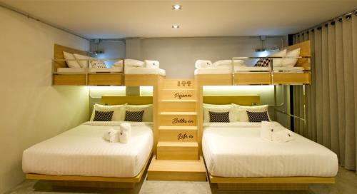 two beds in a room with bunk beds at The Plug Hotel in Nakhon Si Thammarat
