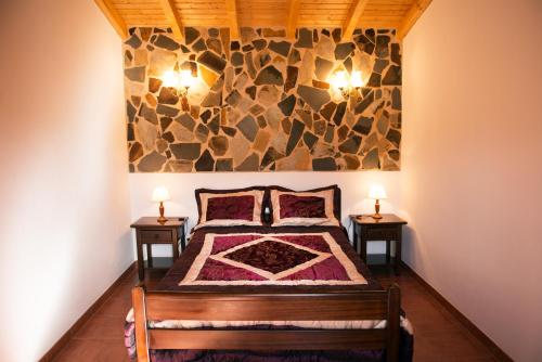 a bedroom with a bed with two lamps on two tables at Recanto Da Ribeira Casas De Campo in Monchique