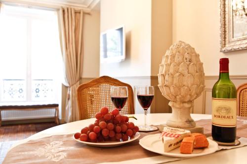 - une table avec une bouteille de vin et une assiette de fruits dans l'établissement Le Triomphe Elysees, à Paris