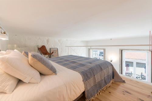 a white bedroom with a large bed with pillows at LovelyStay - Cativo Mezzanine Studio in Porto