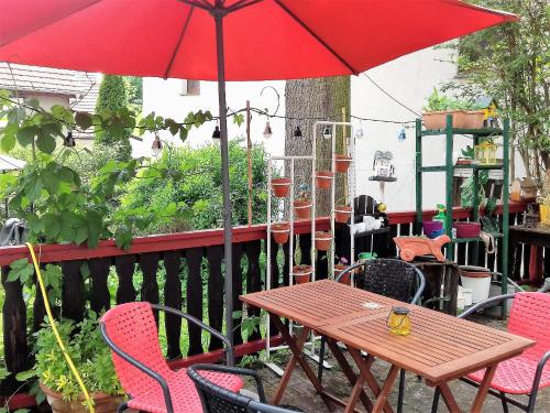 Hotel Bad Langensalza Eichenhof في باد لانغينسالزا: طاولة وكراسي خشبية مع مظلة حمراء
