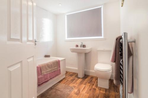 a white bathroom with a toilet and a sink at Riverside View Apartment in Hawick