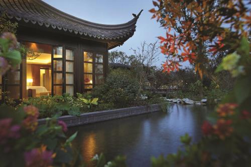 a chinese house with a pond in front of it at Four Seasons Hotel Hangzhou at West Lake in Hangzhou