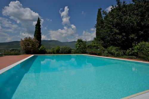 a blue swimming pool with trees and mountains in the background at Agriturismo Parco Fiorito in Cortona