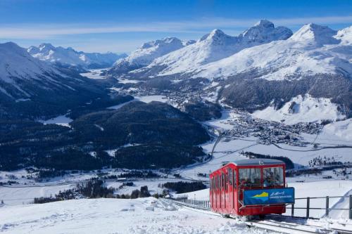 a red and blue train on a snowy mountain at Romantik Hotel Muottas Muragl in Samedan