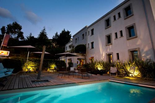 un hotel con piscina frente a un edificio en Rossi Hôtel en Sartène