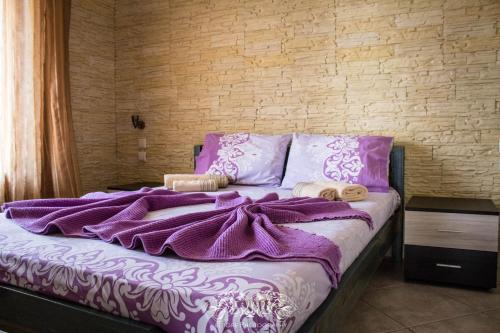 a bed with purple blankets and pillows on it at Villa Alexander in Nea Vrasna