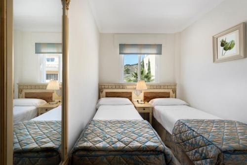 Pokój z 3 łóżkami i lustrem w obiekcie Colina del Paraiso w mieście Estepona
