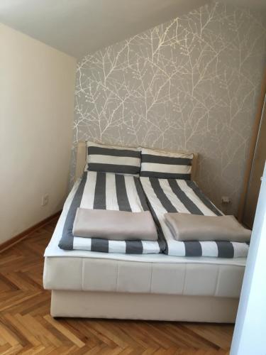 a large bed in a room with a wall at Apartment Niš Center in Niš