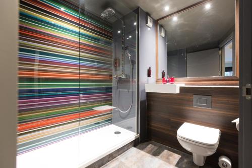 e bagno colorato con doccia e servizi igienici. di Village Hotel Warrington a Warrington