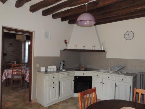 a kitchen with white cabinets and a sink and a table at Ilot Bonheur in Ury