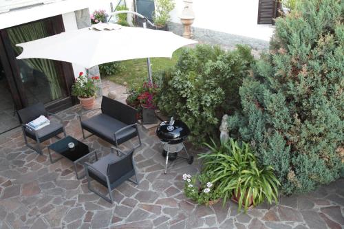 a patio with an umbrella and chairs and a grill at Il Forno Dal 1922 in Bene Vagienna