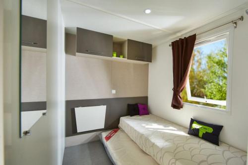 Cette petite chambre comprend un canapé et une fenêtre. dans l'établissement Mobile Home vue baie dans une forêt de pins - La Palmyre, à La Palmyre