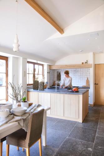 a kitchen with a table and a woman in the sink at B&B de ZIL in Herselt