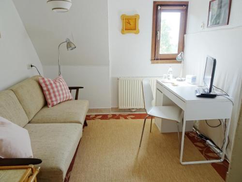 ein Wohnzimmer mit einem Sofa und einem Schreibtisch mit einem Computer in der Unterkunft Haus Fermate in Wilhelmsfeld