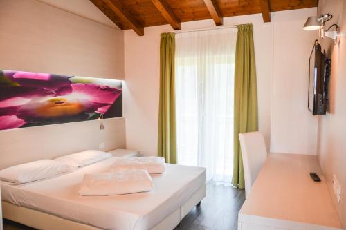 a bedroom with a white bed and a large window at Maso Agritur Santa Lucia in Dro