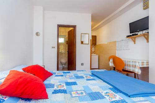 a bedroom with a bed with red and blue pillows at Apartments Nevenka in Krk