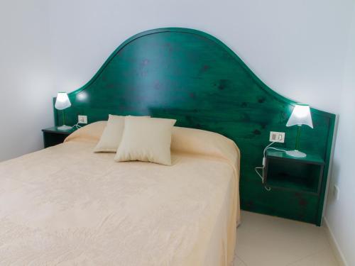 a bedroom with a large bed with a green headboard at Gelso Bianco Apartments in Campofelice di Roccella