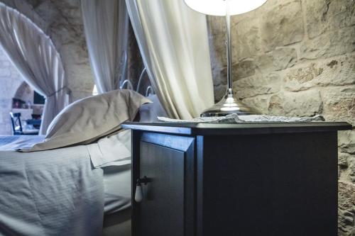 a bedroom with a bed and a table with a lamp at Masseria Rosa Trulli Relais in Alberobello