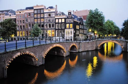 a bridge over a river in a city with buildings at Bed of Roses in Amsterdam