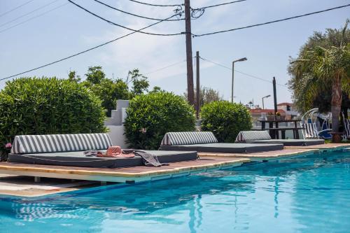 a pool with lounge chairs next to a swimming pool at Malibu Boutique Studios & Bungalows in Faliraki