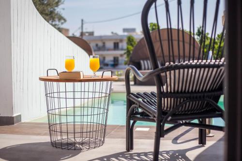 a chair and a table with two glasses of orange juice at Malibu Boutique Studios & Bungalows in Faliraki