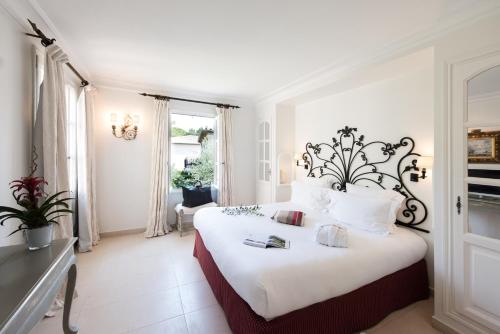 1 dormitorio con 1 cama grande con sábanas y almohadas blancas en Hôtel De Mougins, en Mougins