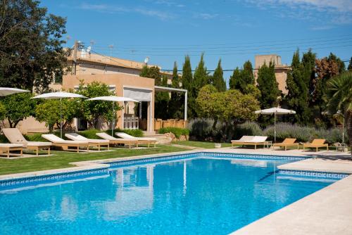 a swimming pool with chairs and umbrellas next to a building at Hotel Ca'n Bonico in Ses Salines