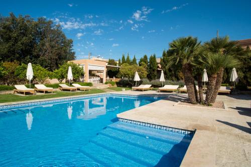 a swimming pool with chaises and umbrellas at Hotel Ca'n Bonico in Ses Salines