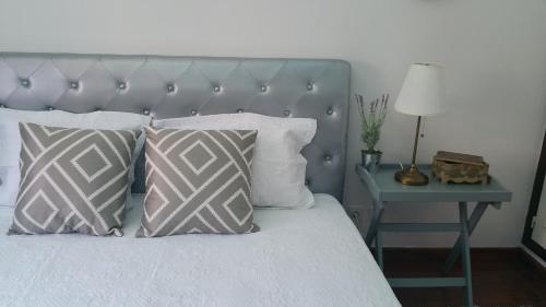 a bed with two pillows and a table with a lamp at Arrabida´s Sweet Home in Azeitao