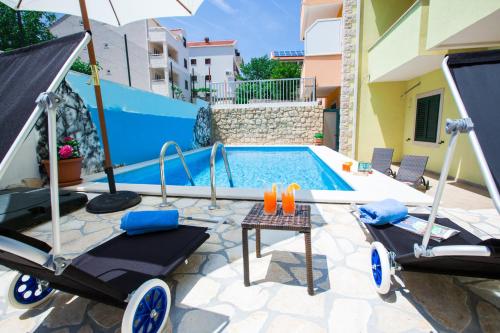 a swimming pool with two chairs and an umbrella at Sunrise Apartments in Cavtat
