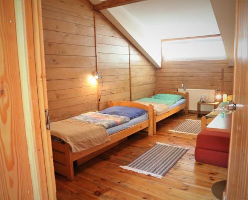 um quarto com 2 camas num quarto com paredes de madeira em Gospodarstwo Agroturystyczne Stary Młyn Wilczkowice em Michalowice