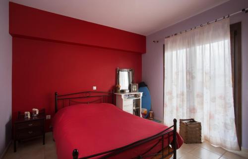 1 dormitorio con paredes rojas y 1 cama con colcha roja en Myriam Spa & Luxury Suites, en Monemvasia