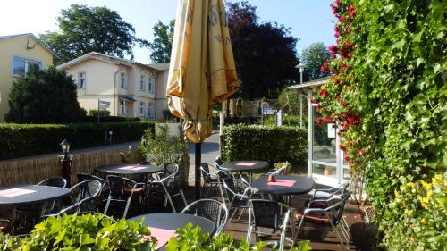 een patio met tafels en een parasol bij Baltisches Haus Pension Moll in Zinnowitz