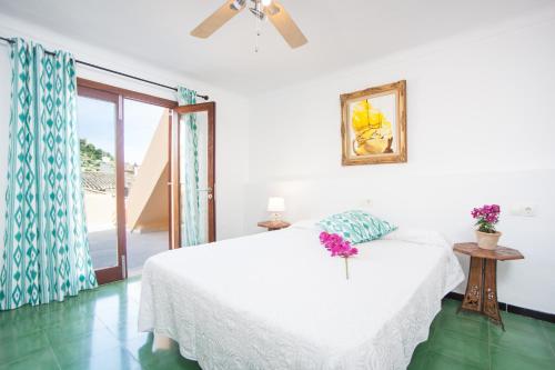 アルタにあるCasa Ses Barraquesの白いベッドルーム(花の飾られたベッド付)