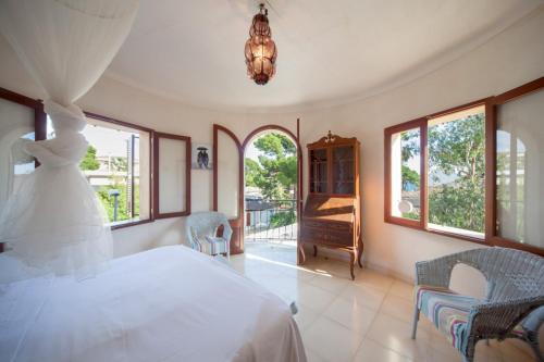 a bedroom with a white bed and some windows at Can Xim in Cala Millor