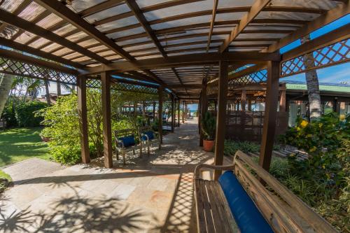 a wooden pergola with a bench in a garden at Costa Norte Ingleses Hotel in Florianópolis