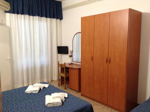 Habitación de hotel con 2 camas y un gran armario de madera. en Hotel Saponi en Rímini