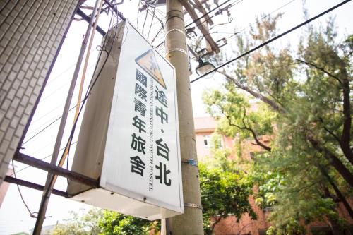 a street sign on a pole in front of a building at On My Way - Taipei Hostel in Taipei