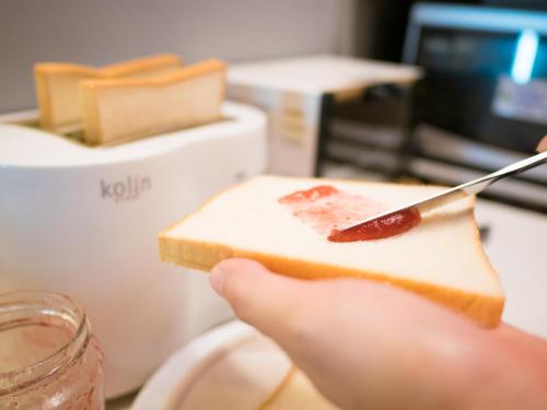 a person holding a piece of bread with a knife at On My Way - Taipei Hostel in Taipei